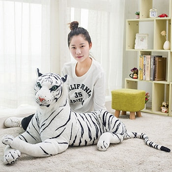 Giant lifelike white tiger plush toy resting on the floor.