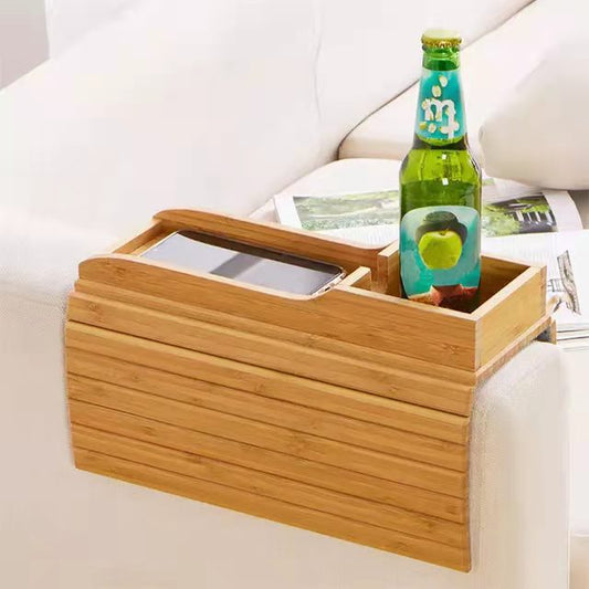 Bamboo sofa tray table with a cup holder and phone slot resting on a couch armrest.