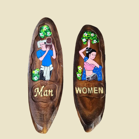 A pair of hand-carved teak wood restroom signs featuring traditional Thai man and woman figures.