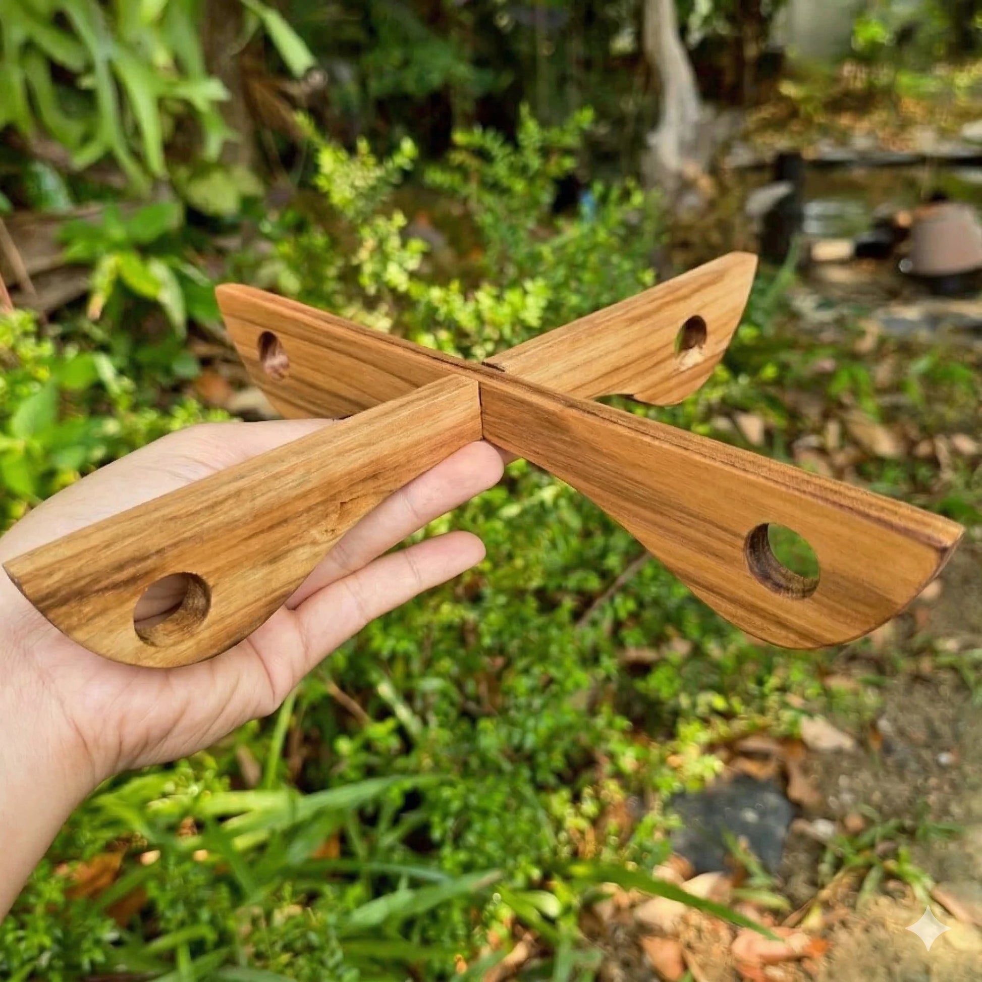 Collapsible Teak Wood cross-shaped trivet on a natural wood background
