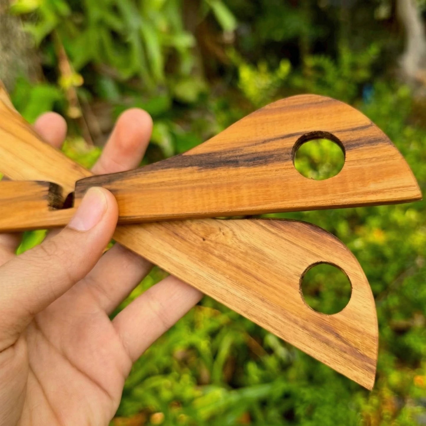 Collapsible Teak Wood cross-shaped trivet on a natural wood background