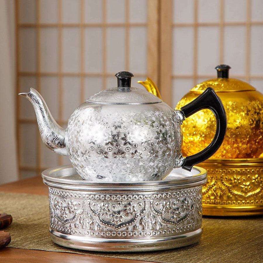 Exquisite vintage Thai tin teapot set resting on a matching embossed pedestal in a tea room.