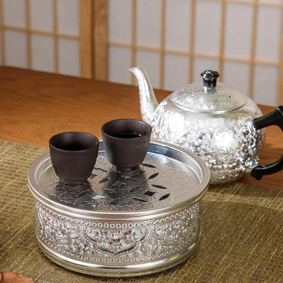 Close-up of the rich, hand-pressed traditional Thai chisel pattern on a silver tin alloy teapot base.