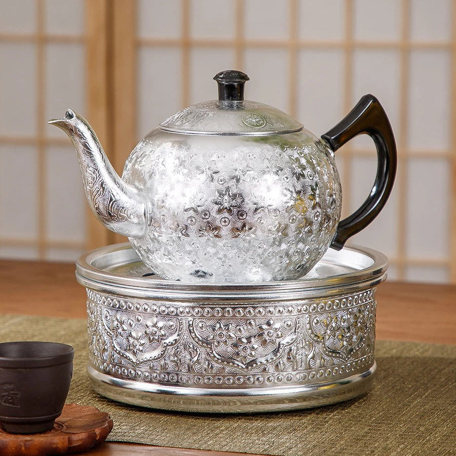 Close-up of the rich, hand-pressed traditional Thai chisel pattern on a silver tin alloy teapot base.