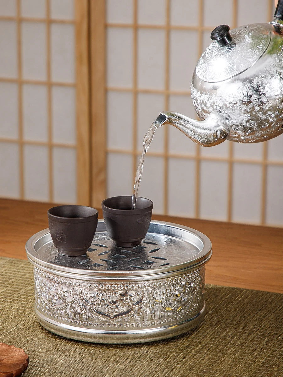 Close-up of the rich, hand-pressed traditional Thai chisel pattern on a silver tin alloy teapot base.