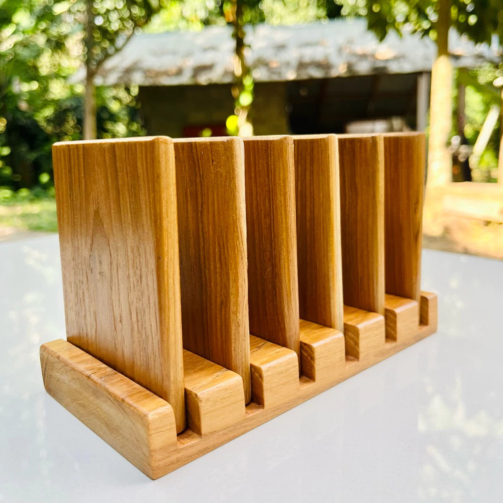 Handmade 7-piece golden teak wood coaster set with a vertical storage rack, featuring natural wood grain and water-resistant coating.