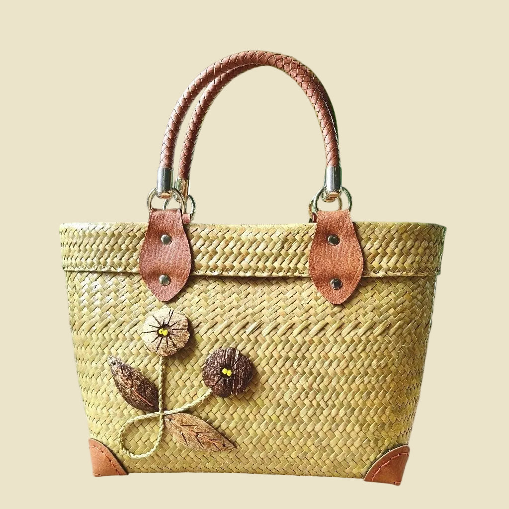 Handmade woven Krajood sedge tote bag with braided tan handles and coconut shell embroidery, eco-friendly Thai straw bag.