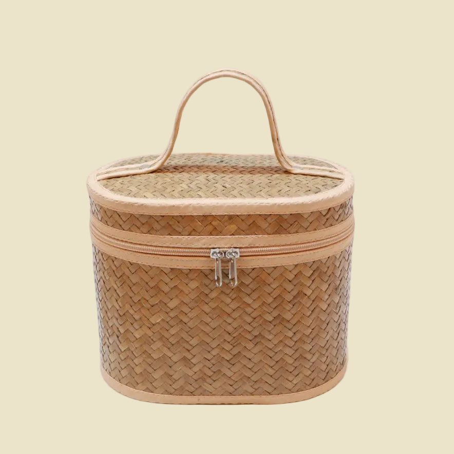 Handwoven natural reed vanity case with a top handle and zipper closure, perfect for makeup organization.