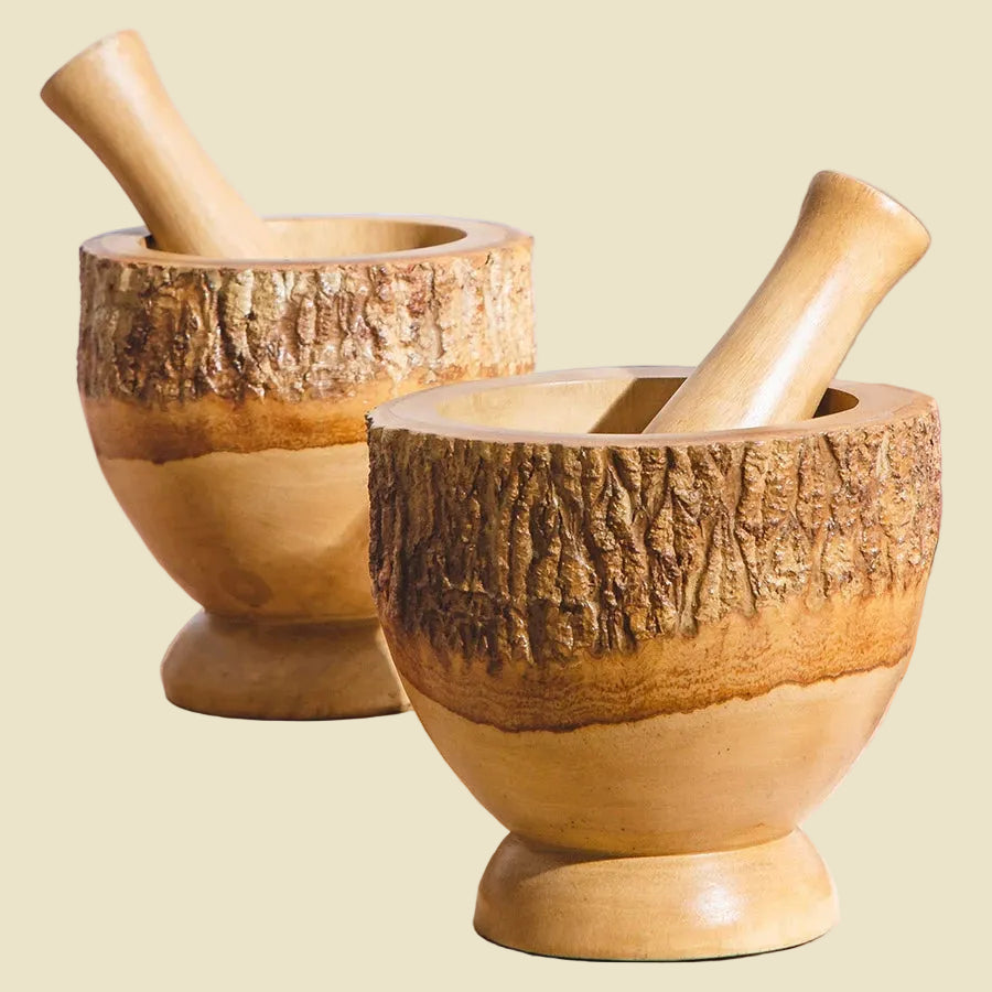 Rustic heavy-duty solid wood mortar and pestle set with natural bark edge on a wooden kitchen counter.