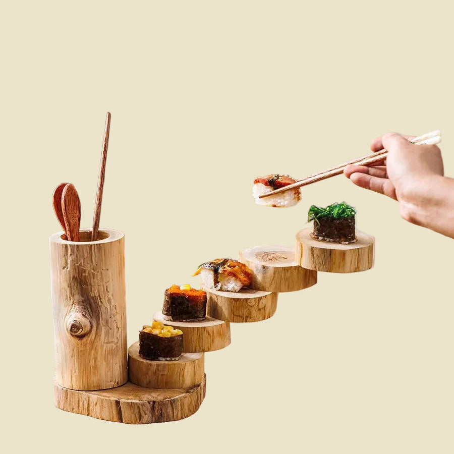 Person using chopsticks to pick up sushi from a food-safe unpainted wooden tiered serving tray.