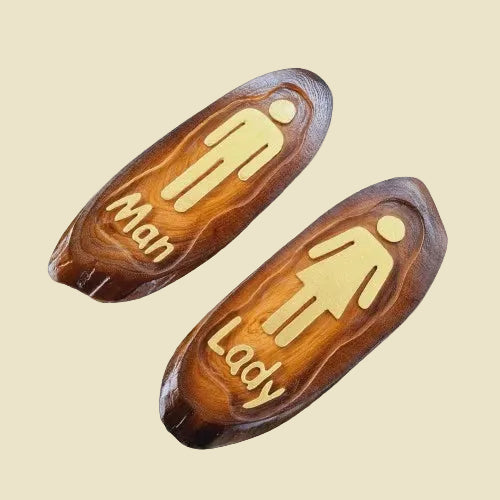A pair of rustic teak wood restroom door signs with carved Man and Lady figures and natural wood grain.