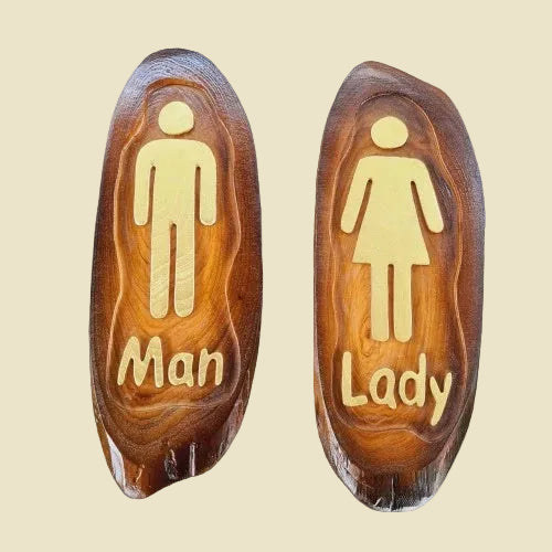 A pair of rustic teak wood restroom door signs with carved Man and Lady figures and natural wood grain.
