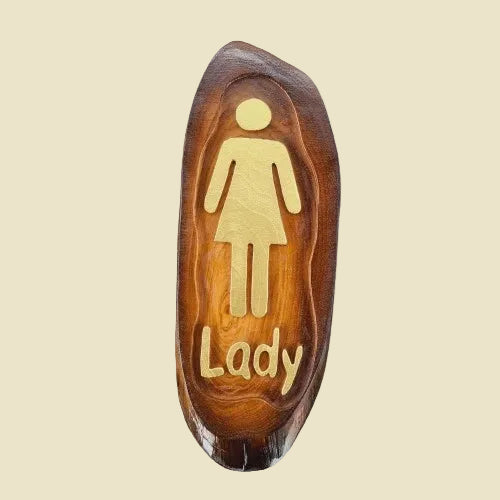 A pair of rustic teak wood restroom door signs with carved Man and Lady figures and natural wood grain.