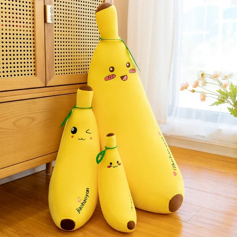 Three yellow giant banana plush body pillows in different sizes, featuring cute kawaii embroidered faces