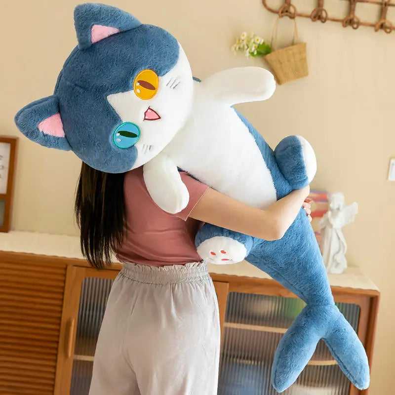 A woman sleeping comfortably on a bed while hugging a giant blue shark cat plush body pillow.