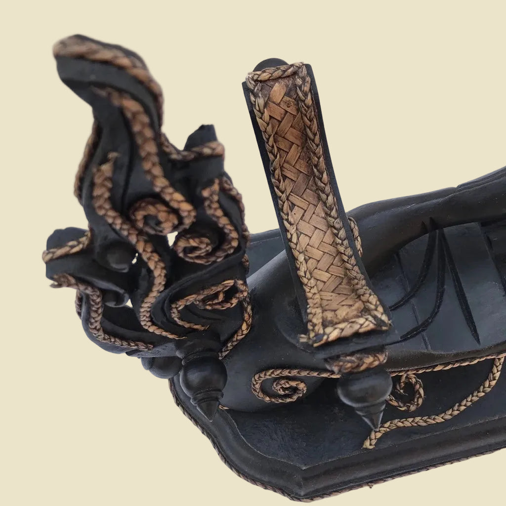 Unique handcrafted Thai Rain Tree wood wine bottle holder in a hand-shaped design with woven rattan accents, displayed on a tabletop.