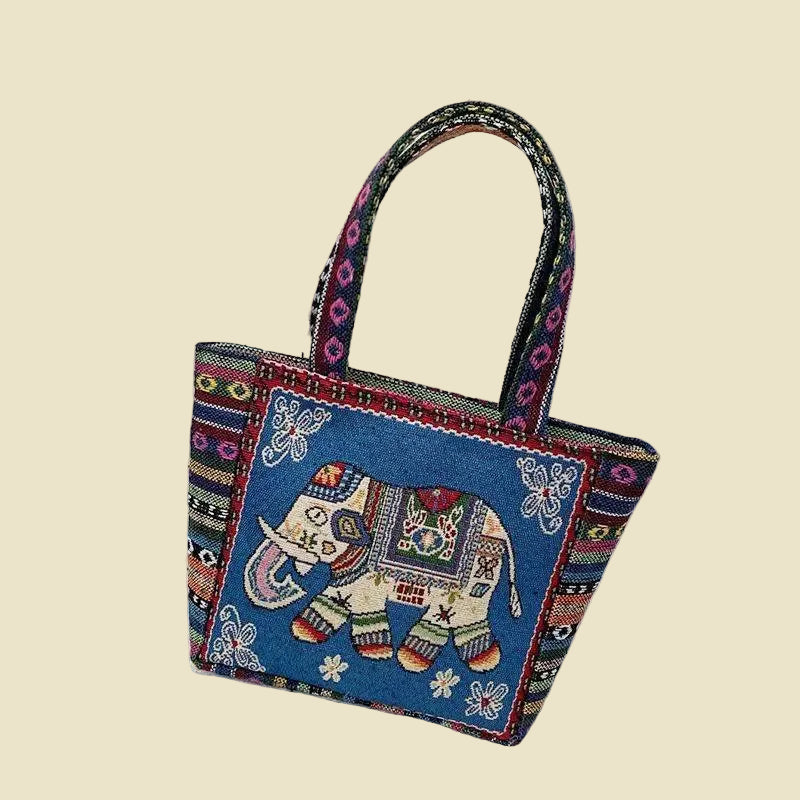 Woven canvas tote bag with colorful Thai elephant embroidery, featuring a zipper and boho-inspired design.
