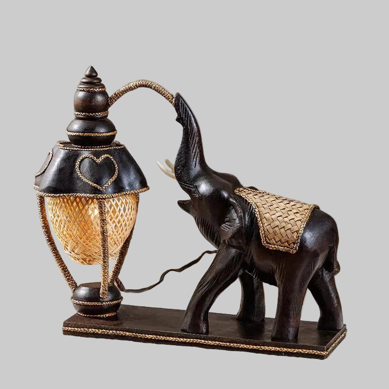 Handcrafted wooden elephant table lamp with a woven bamboo shade lighting up a rustic living space.