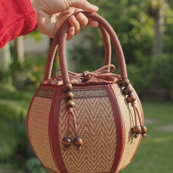 Woman carrying a 6-inch pumpkin-shaped straw woven bag on her wrist.