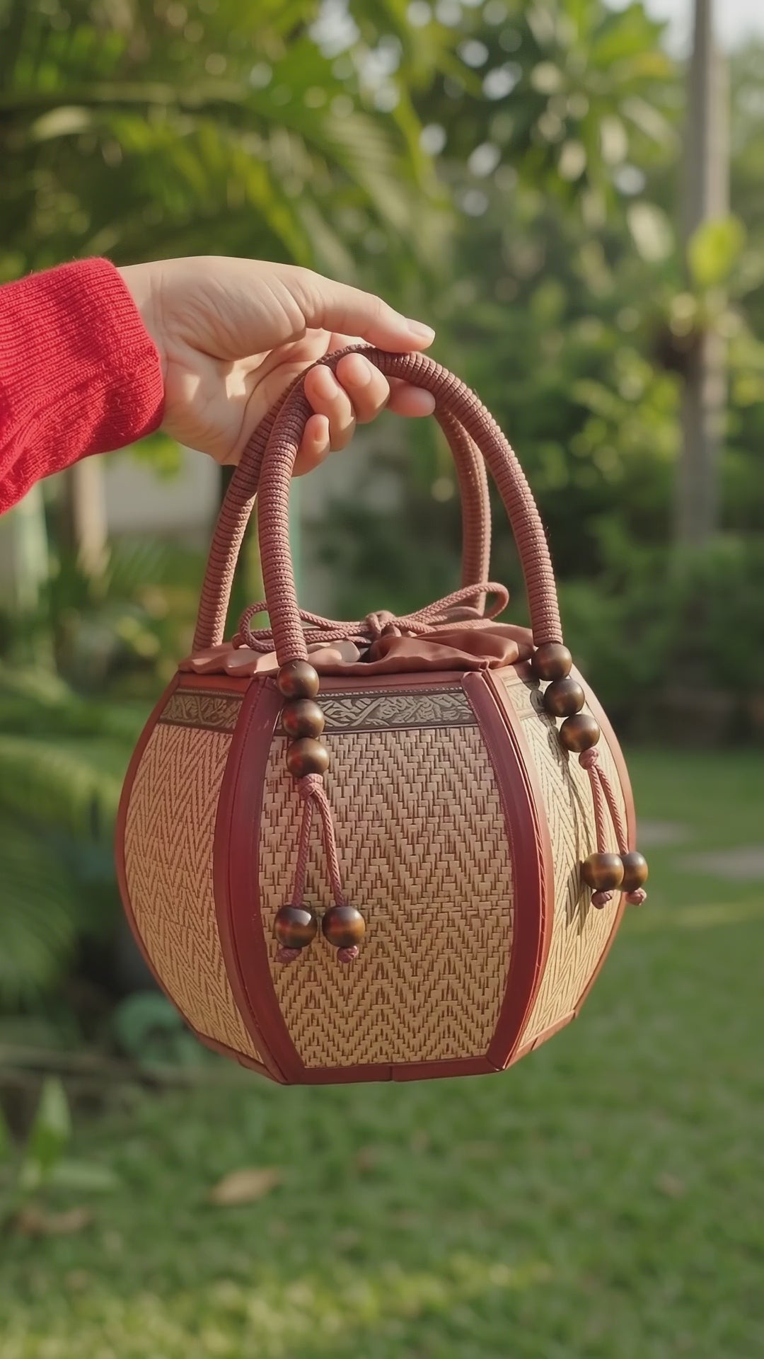 Woman carrying a 6-inch pumpkin-shaped straw woven bag on her wrist.