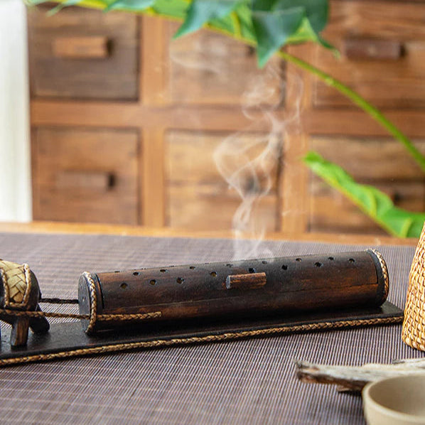 wooden elephant enclosed incense burner with smoke rising from 18 holes
