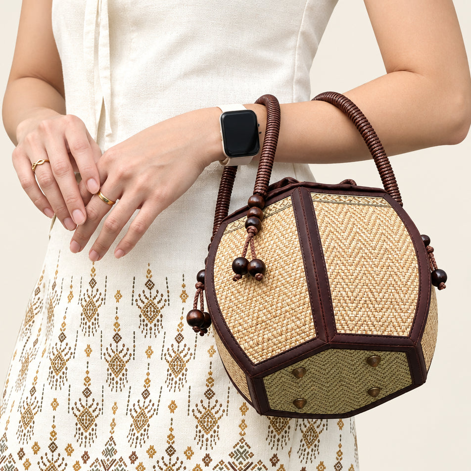 Woman carrying a 6-inch pumpkin-shaped straw woven bag on her wrist.