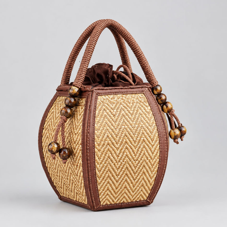 Handmade pumpkin-shaped woven reed bag featuring a top drawstring closure and brown trim.